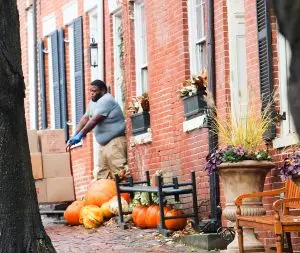 Envelop by McClain mover transporting boxes with a hand truck outside a historic brick rowhome on Prince Street in Old Town Alexandria