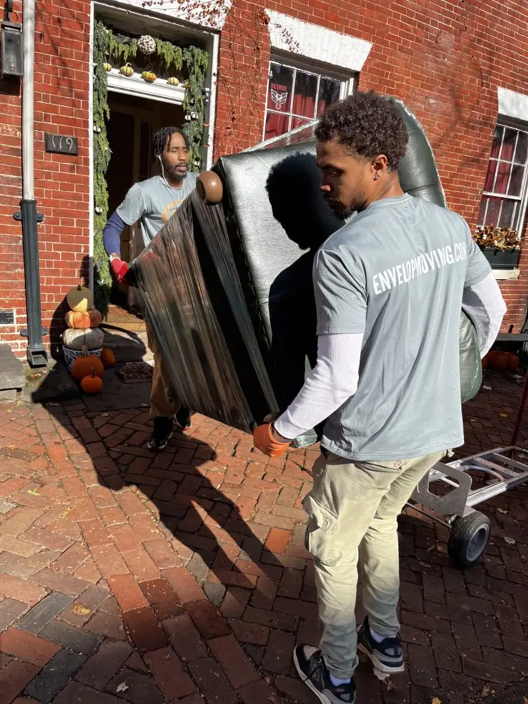 Envelop by McClain movers carrying a wrapped sofa out of a home at 119 Prince Street in Old Town Alexandria